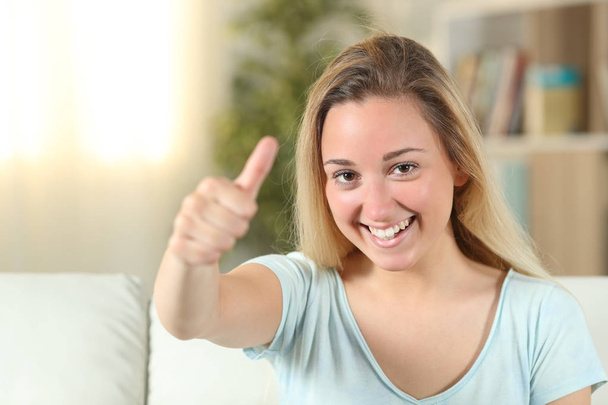 Happy teenage girl with thumbs up at home - Фото, изображение