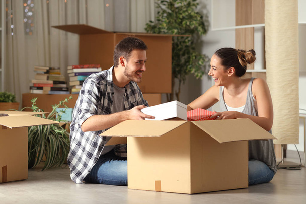Happy couple unboxing belongings moving house looking each other - Foto, Imagem