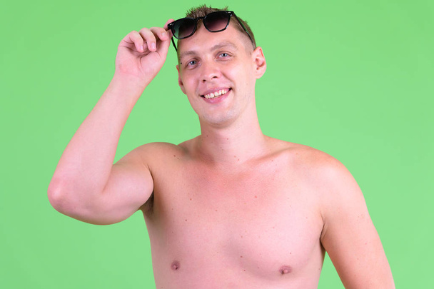 Retrato de un joven sin camisa feliz quitándose las gafas de sol
 - Foto, imagen