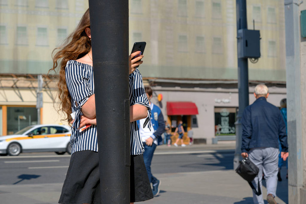 Dziewczyna z pięknymi kręcone włosy rozmawiają na telefon komórkowy na ruchliwej ulicy. - Zdjęcie, obraz