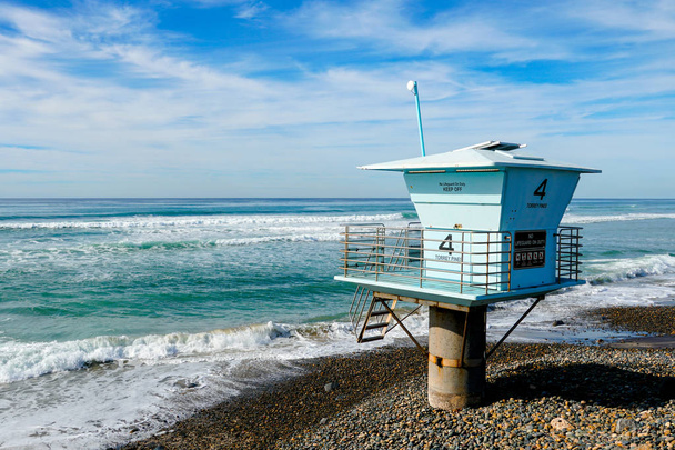 Sininen hengenpelastaja torni numero 4 kallioisella hiekkarannalla, jossa on pilvinen sininen taivas aurinkoinen päivän päätteeksi, Torrey Pines State Beachillä Kaliforniassa, joka sijaitsee San Diegon piirikunnassa
. - Valokuva, kuva