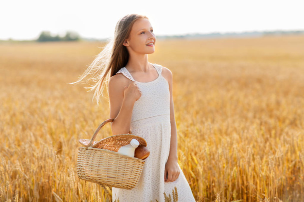 girl with bread and milk in basket on cereal field - Foto, Imagem