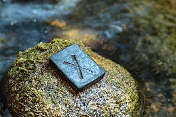 Rune nordique Gebo (Gibu) sur la pierre et le fond de la rivière soir. Cadeau, équilibre, harmonie, don. La rune est associée au Dieu Suprême Scandinave Odin
. - Photo, image