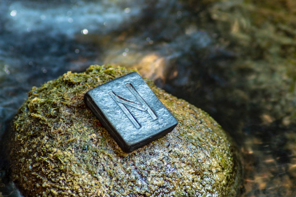 Norse rune Hagalaz (Hagal) on the stone and the evening river background. Excitement, shake, exit the comfort zone. Getting rid of old unnecessary patterns. - Photo, Image