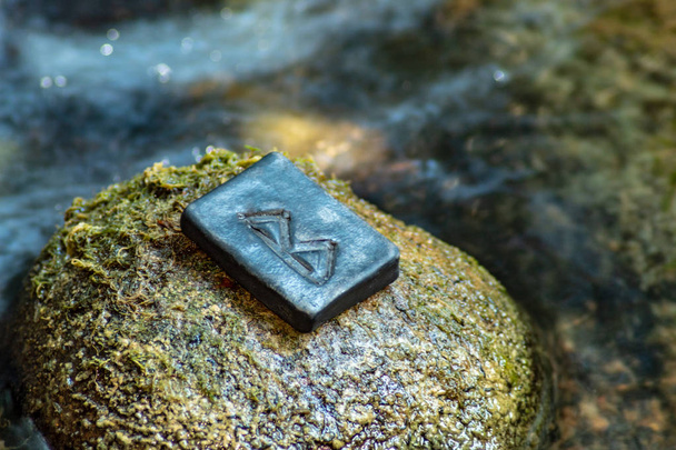 Runa nórdica Bercana en la piedra y el fondo del río por la noche. Abedul, feminidad, cuidado maternal y protección. La runa está asociada con la diosa escandinava Frigg
. - Foto, imagen