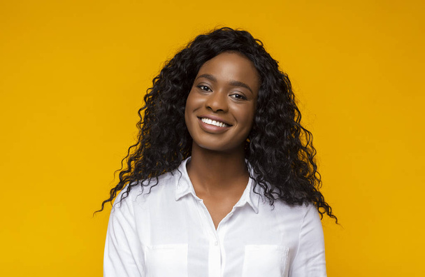 Jonge lachende Afro-Amerikaanse vrouw over gele achtergrond - Foto, afbeelding