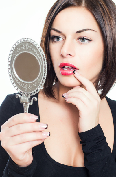 Beautiful brunette girl looks in mirror - Fotó, kép