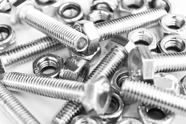 Metal bolts and nuts  in a row background. Chromed screw bolts and nuts isolated. Steel bolts and nuts pattern. Set of Nuts and bolts. Tools for work. Black and white - Zdjęcie, obraz