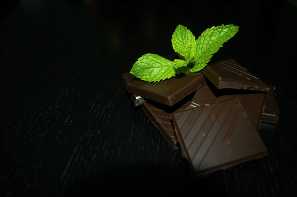 Pile of dark chocolate with fresh mint on the top on black table - Foto, Imagem