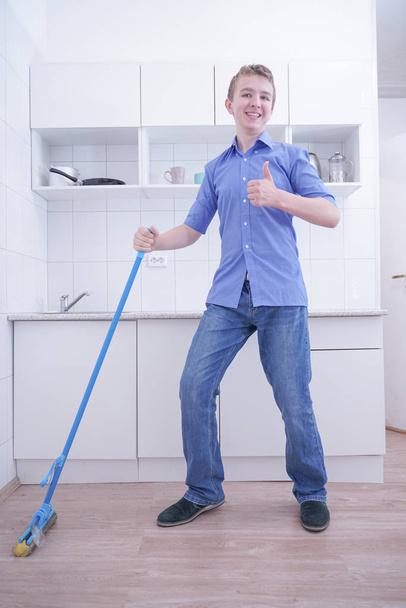 Підліток хлопчик Мотапінг підлозі і допомагає своїм батькам чистити на кухні - Фото, зображення