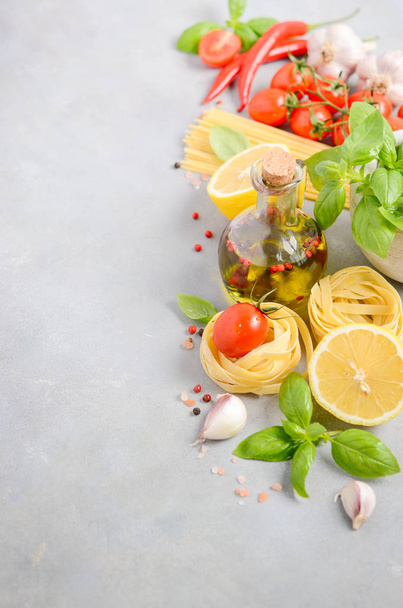 Italian food ingredients  pasta, tomatoes, basil and olive oil on gray concrete background. - Photo, Image