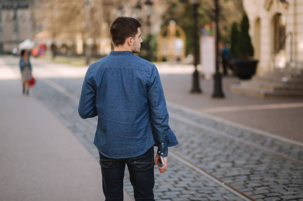 Vista trasera del hombre caminando en el centro de la ciudad. Camisa azul
 - Foto, Imagen