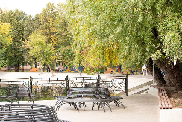 Σιδερένιο μαύρο παγκάκι στο πάρκο το φθινόπωρο - Φωτογραφία, εικόνα