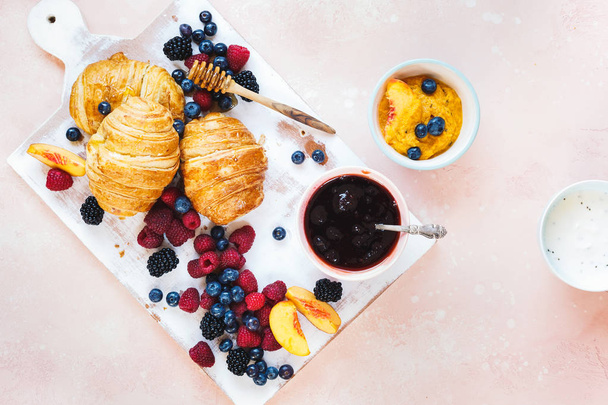 Fruity breakfast. Breakfast with freshly baked croissants, fresh summer berries and honey. Top view, blank space - Fotó, kép
