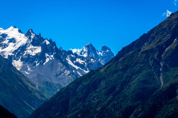Ushba - um dos picos mais visíveis das montanhas do Cáucaso, tem um pitoresco pico duplo na forma de uma torre. Devido ao seu perfil íngreme, Ushba é considerada a escalada mais difícil do Cáucaso
. - Foto, Imagem