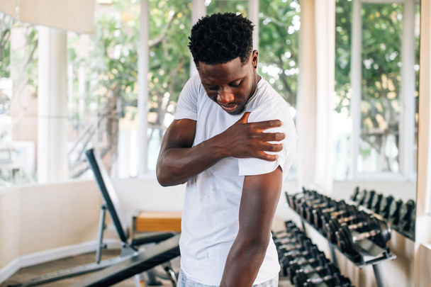 Sportsman holding painful shoulder in gym - Foto, Bild