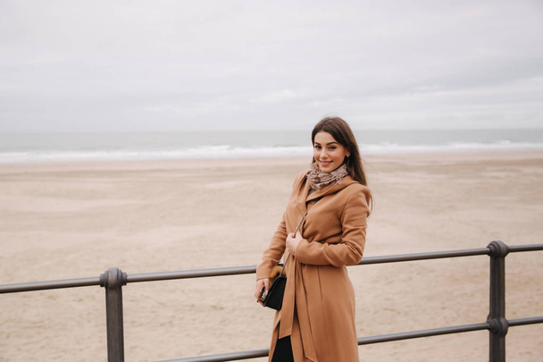 Stylish lady with make up in beautiful coat standing along North Sea. Woman smile - Foto, afbeelding