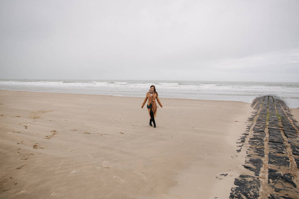 Szczęśliwa kobieta Walkin na plaży wzdłuż Morza Północnego. Na zewnątrz jest zimny i deszczowy - Zdjęcie, obraz