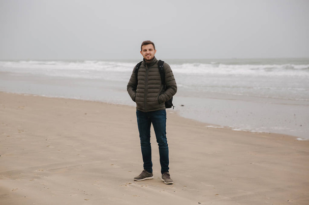 Promenade touristique masculine le long de la mer du Nord. Homme avec sac à dos debout sur la côte par temps pluvieux. Belle mer
 - Photo, image