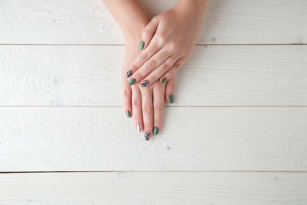 manos de las mujeres con una hermosa manicura en un fondo de madera clara
 - Foto, Imagen