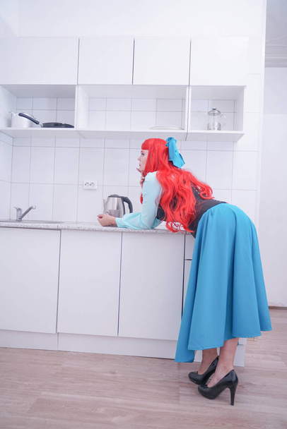 jeune fille aux cheveux roux en robe bleue avec corset noir sur la cuisine
 - Photo, image