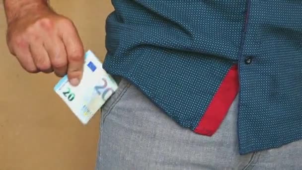 Egy férfi az euróbankjegyeket a nadrágzsebébe helyezi. Egy férfi elrejti pénzt a zsebében. - Felvétel, videó