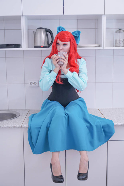 jeune fille aux cheveux roux en robe bleue avec corset noir sur la cuisine
 - Photo, image
