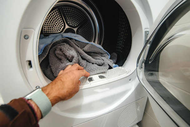 Homem mão arranjar roupas na máquina doméstica moderna
 - Foto, Imagem
