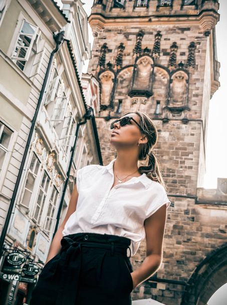A young girl walks through the old city in sunny weather on a background of beautiful architecture. - Fotoğraf, Görsel