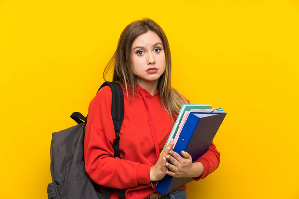 Teenager student girl over yellow background pleading - 写真・画像