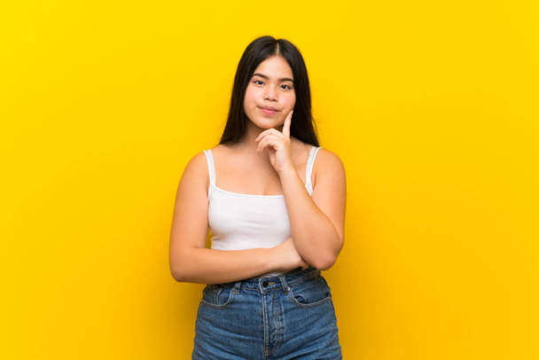 Joven adolescente asiática chica sobre aislado amarillo fondo buscando frente
 - Foto, imagen