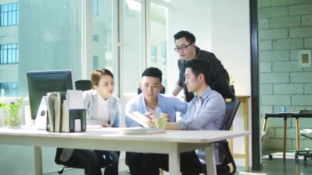 quatro jovens empresários asiáticos reunidos no escritório discutindo negócios no escritório de pequena empresa
 - Filmagem, Vídeo