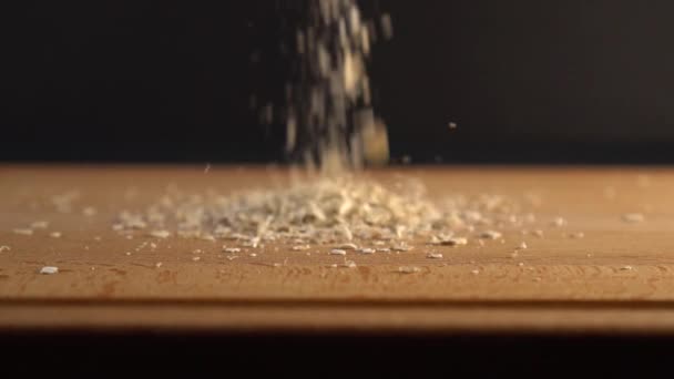 Oatmeal fall on a wooden surface on a black background. Cooking diet breakfast - Video