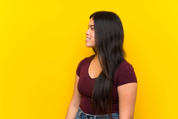 Νέος έφηβος Ασιάτης/ισσα κορίτσι πάνω από απομονωμένο κίτρινο φόντο κοιτάζοντας προς την πλευρά - Φωτογραφία, εικόνα