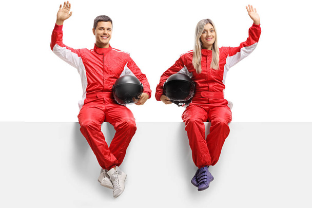 Male and female car racers sitting on panel and waving - Φωτογραφία, εικόνα