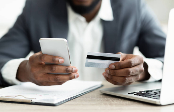 Homem de negócios sério pagando suas contas on-line usando o aplicativo no smartphone
 - Foto, Imagem