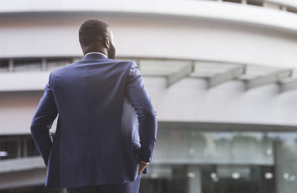 Zelfverzekerde zwarte zakenman tegen moderne kantoor centrum achtergrond - Foto, afbeelding