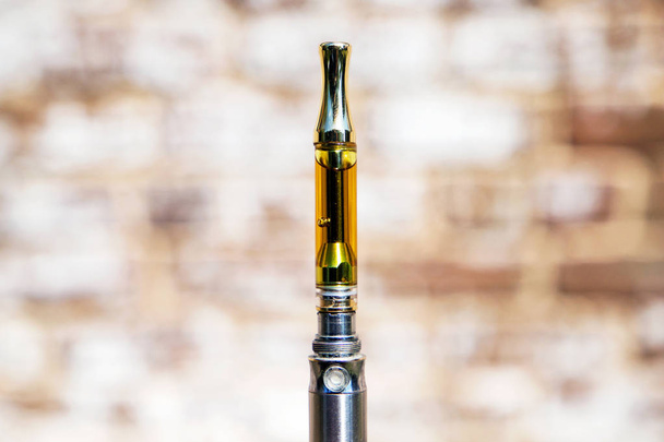 Elektronische Zigarette mit Cannabisöl auf verschwommenem natürlichen Hintergrund - Foto, Bild
