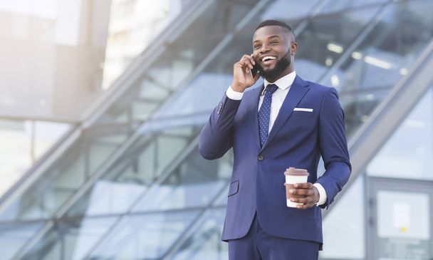 Черный бизнесмен говорит по телефону проведение кофе Кубок в городе
 - Фото, изображение