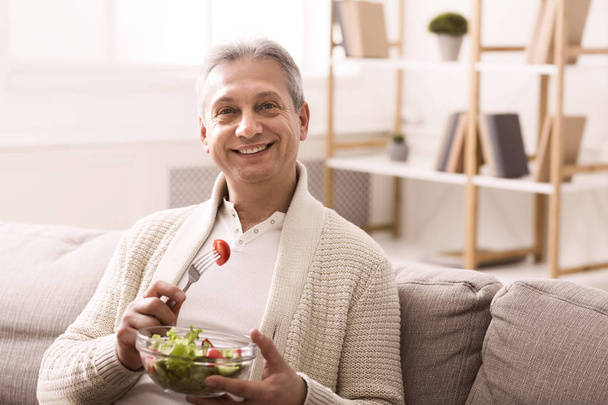 Egészséges táplálkozás. Boldog vezető férfi étkezési friss zöldség saláta - Fotó, kép