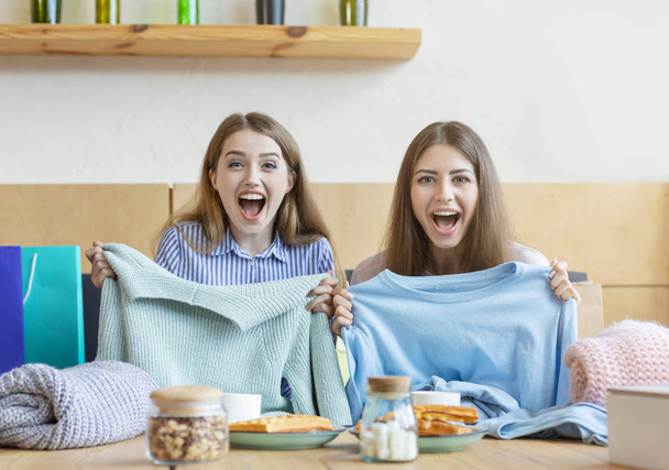 Σοκαρισμένος κορίτσια με το στόμα ορθάνοιχτα δείχνοντας νέα πουλόβερ - Φωτογραφία, εικόνα