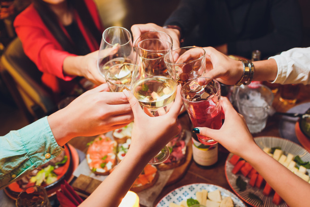 Mani umane con bicchieri di vino rosso che li afferrano sul tavolo servito
. - Foto, immagini