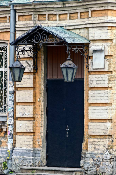 Stare czarne drzwi z dwoma światłami ulicznymi na elewacji budynku - Zdjęcie, obraz