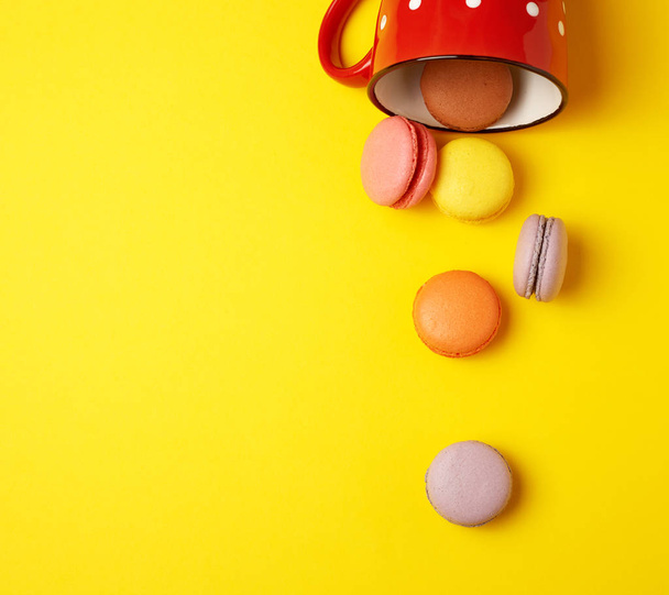 round multicolored macarons falling from a red ceramic cup  - Foto, afbeelding