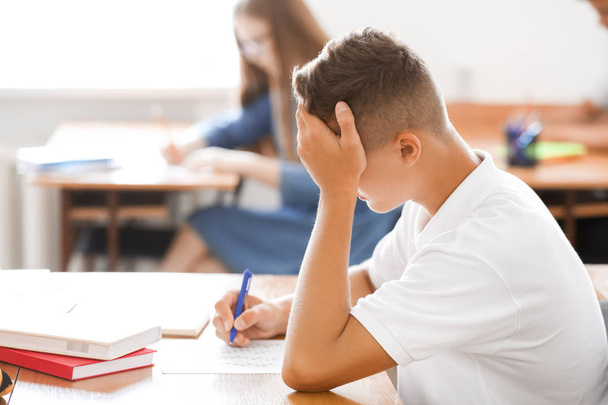 Tizenéves fiú elhaladó iskolai teszt az osztályban - Fotó, kép