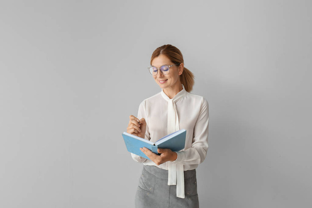 Beautiful female teacher with book on light background - Photo, Image