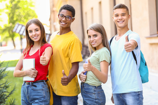 Portrait of young students showing thumb-up outdoors - Photo, image