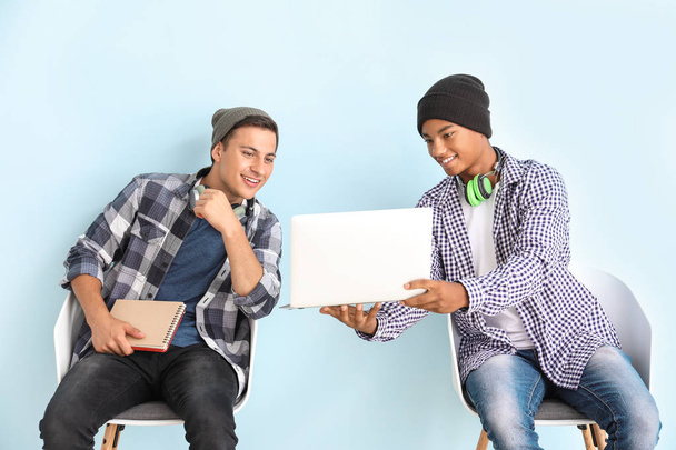Porträt junger Studenten mit Laptop auf farbigem Hintergrund - Foto, Bild