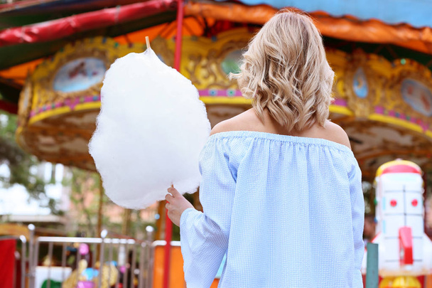 Mulher com doce algodão doce no parque de diversões, visão traseira
 - Foto, Imagem