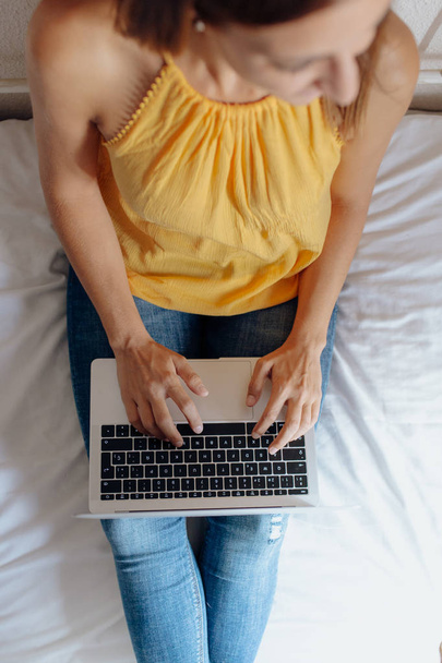 Unrecognizable woman sitting on the bed typing on the laptop - Foto, Bild
